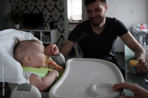 Baby girl eating lunch with help of her father. photo