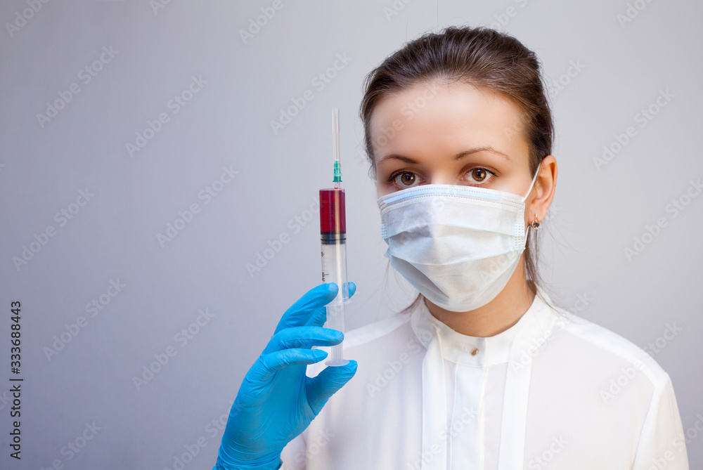 young girl doctor holding syringe with blood in his hand in mask on her face young girl doctor holding syringe with blood in his hand in mask on her face