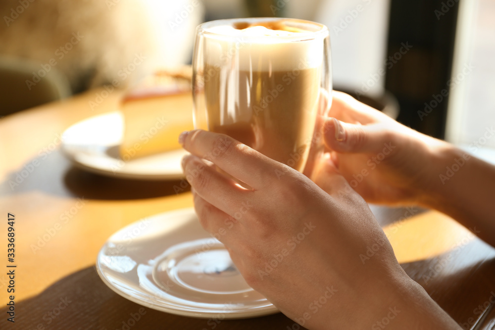 Woman with cup of delicious latte at table, closeup Woman with cup of delicious latte at table, closeup