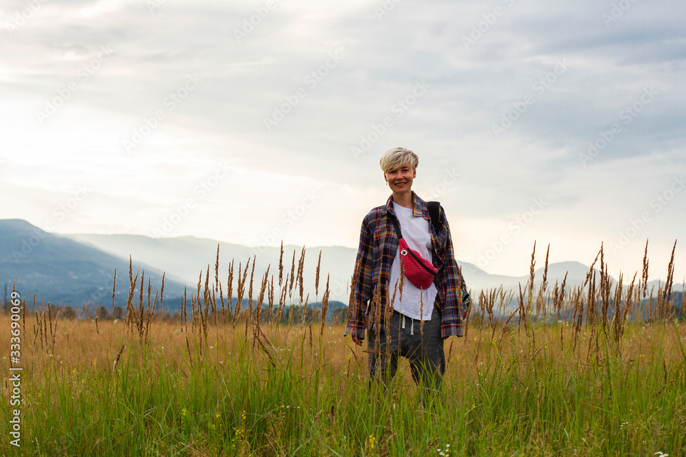 happy woman traveler stands in field