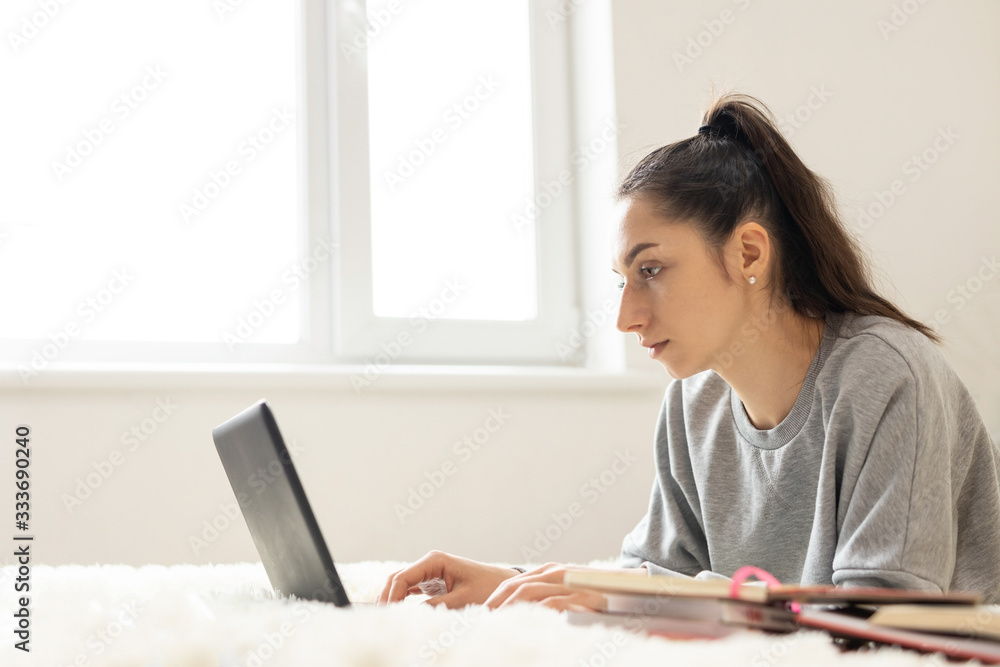 Young girl woman on the bed, distance learning for students. Coronavirus. Quarantine. Woman look at a laptop computer. Freelancer, distant work, work at home, online education Young girl woman on the bed, distance learning for students. Coronavirus. Quarantine. Woman look at a laptop computer. Freelancer, distant work, work at home, online education