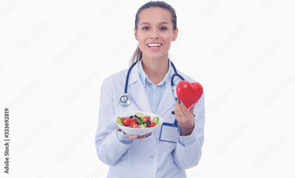 Portrait of a beautiful woman doctor holding a plate with fresh vegetables and red heart. Woman doctors. Portrait of a beautiful woman doctor holding a plate with fresh vegetables and red heart. Woman doctors.