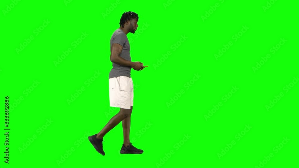 African american man walking and texting message vie his mobile phone at Green Screen, Chroma Key. Profile view. African american man walking and texting message vie his mobile phone at Green Screen, Chroma Key. Profile view.