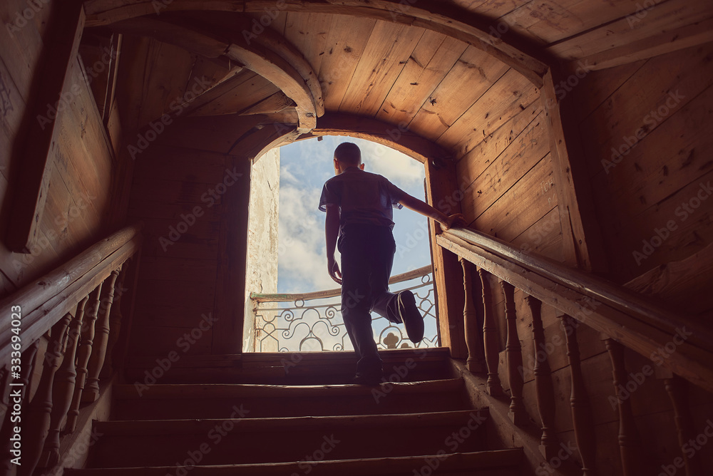 boy goes to the balcony on the stairs in a wooden house