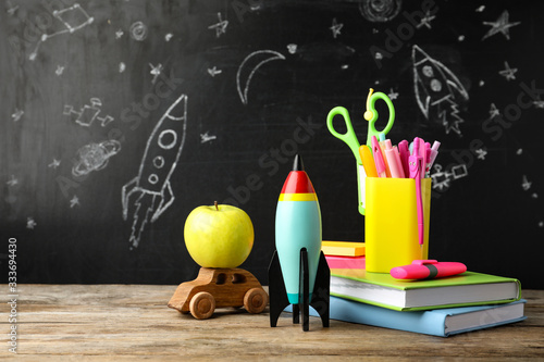 Bright toy rocket, car and school supplies on wooden table