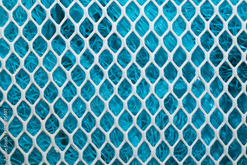 Metal enameled grid. abstract background. blue cloth behind the metallic grate