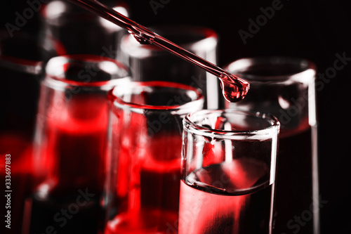 Laboratory test tube background. Covid-19 corona virus pandemic crisis. Glass pipette fluid drop. Global disease problem. Vaccine research science texture. Shiny crystal glass isolated on black.