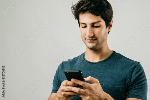 Excited bearded man Brazilian in Wear t-shirt playing on smartphone over jovial Smiley To be happy Chat with your girlfriend Play the game white background