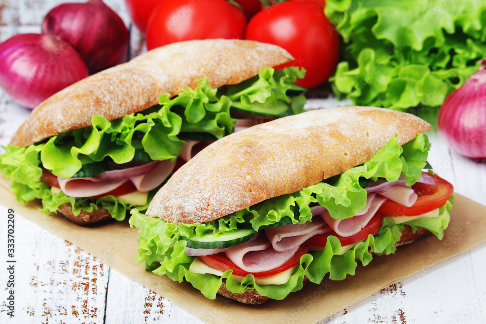 Two sandwiches with fresh vegetables, ham and cheese in ciabatta bread Two sandwiches with fresh vegetables, ham and cheese in ciabatta bread