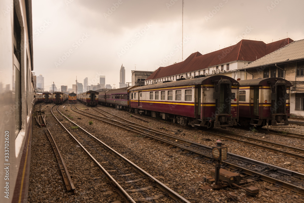 Old trains on a hazy day in Bangkok central train station. Skyscrapers in distance. Arrival from Don Mueang International Airport. No sunlight,