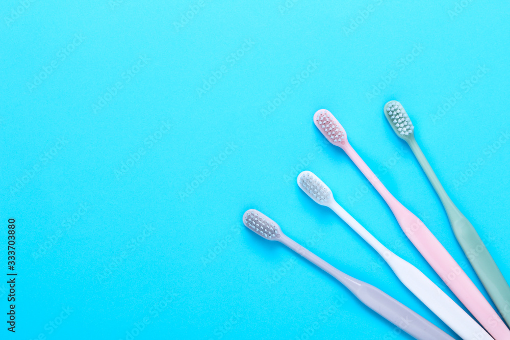 Pink, green, white and gray toothbrushes on blue background. Taking care of teeth, dental concept. Flat lay photo, copy space, top view. Pink, green, white and gray toothbrushes on blue background. Taking care of teeth, dental concept. Flat lay photo, copy space, top view.
