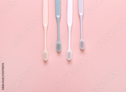 Pink, green, white and gray toothbrushes on pink background. Taking care of teeth, dental concept. Flat lay photo, copy space, top view.