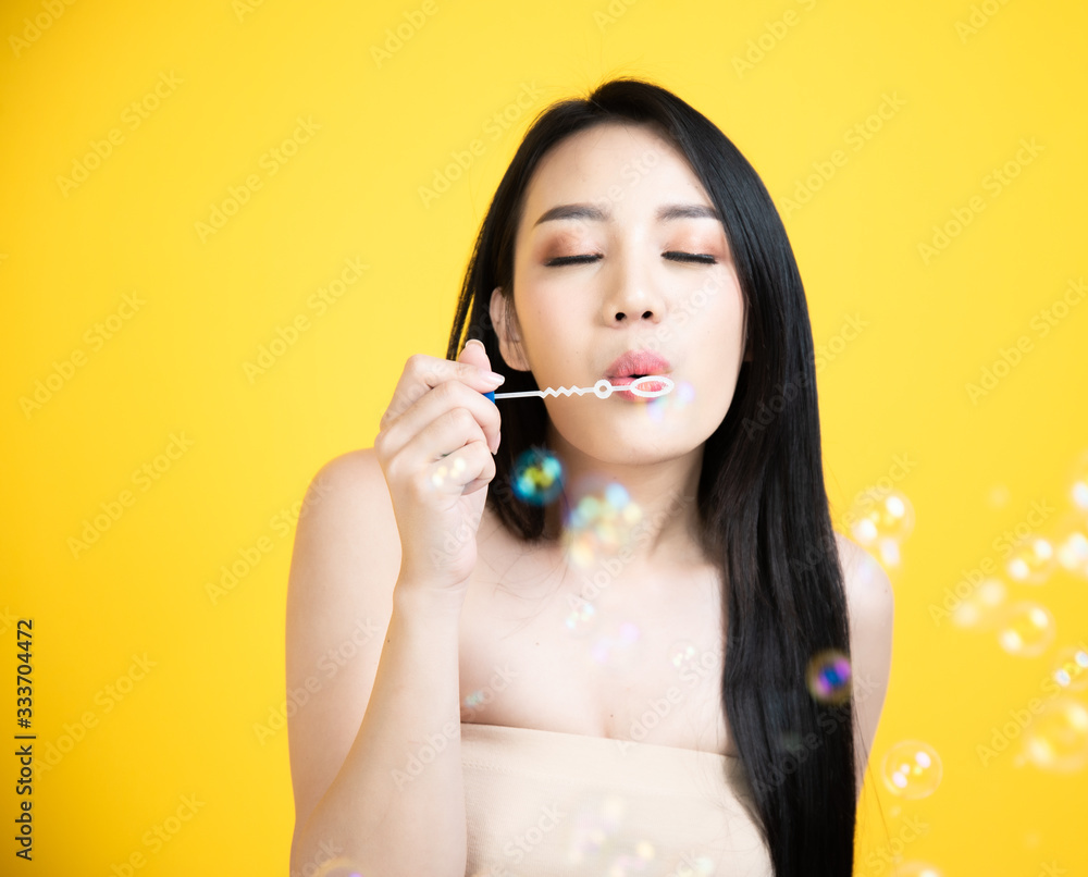 portrait asian woman smile face Blowing Bubbles with yellow background portrait asian woman smile face Blowing Bubbles with yellow background