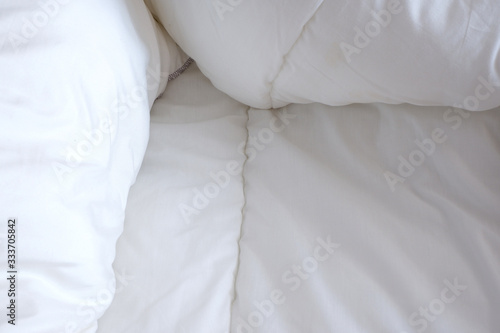 Soft white blanket. The sun's rays fall on the bed linen. Cosiness