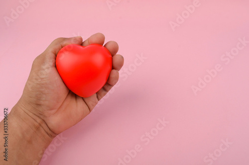 Fototapeta Naklejka Na Ścianę i Meble -  Health concept. Hand holding red heart on pink background. Selective focus.