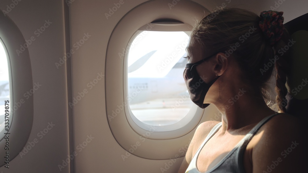 Woman travel caucasian at plane with wearing protective medical mask. Girl tourist at aircraft with protect respirator. Concept virus protection coronavirus epidemic sars-cov-2 covid-19 2019-ncov.