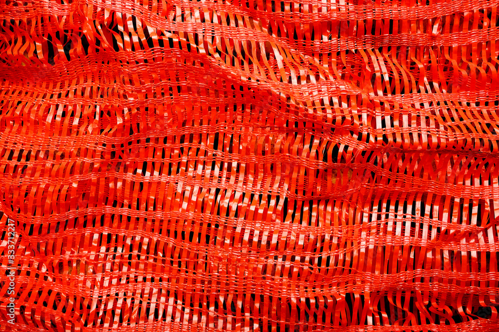 Fototapeta premium Red synthetic woven texture. Woven background in Lash Lava. Synthetic sack texture.