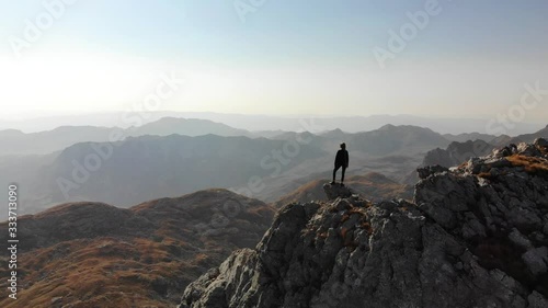 Girl standing on a mountain ridge. Beautiful aerial view of the peaked tops of Durmitor in Montenegro