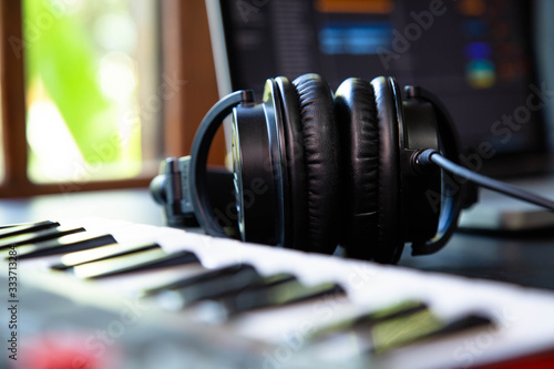 Midi keybard in a music producer home studio, desk with headphones and a notebook. Window with nature in the background. photo