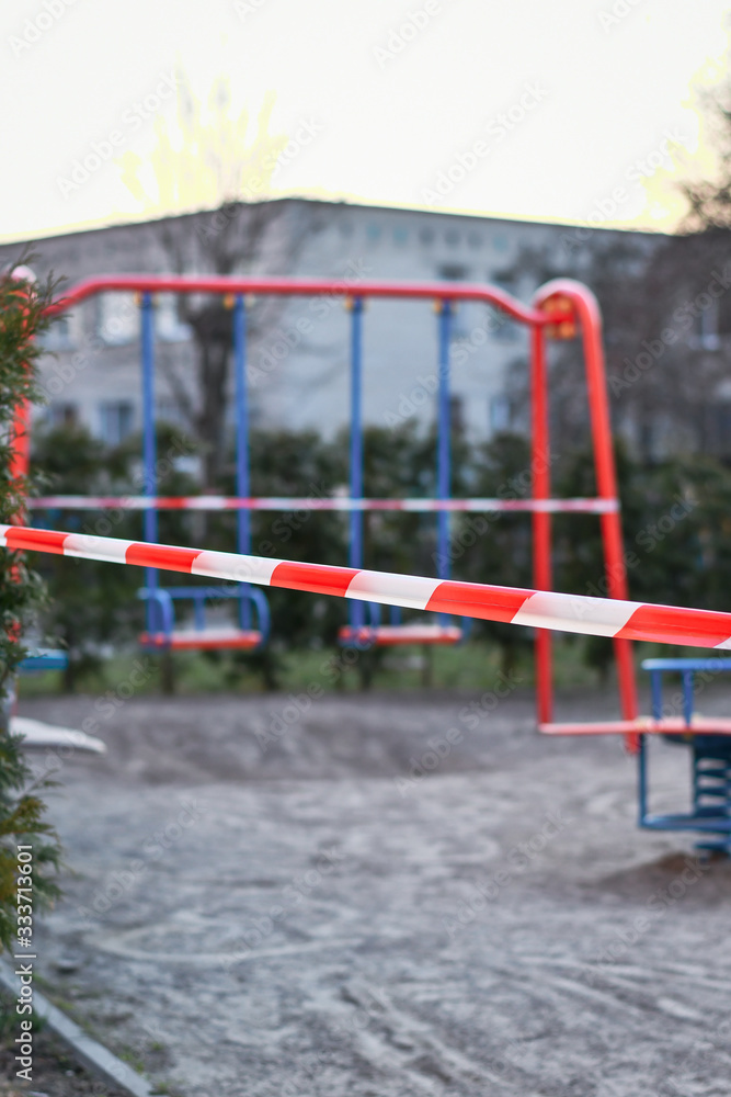Red caution tape on kids playground, closed due to COVID-19 quarantine. Selective focus. Red caution tape on kids playground, closed due to COVID-19 quarantine. Selective focus.