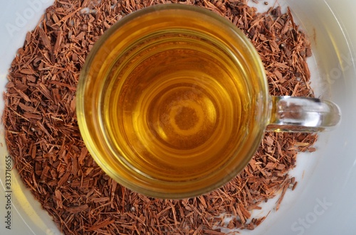 A glass of catuaba tea on a white plate with a catuaba bark photo