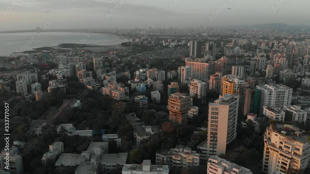 Drone shot of the densely populated Mumbai City with an airplane taking off in the background