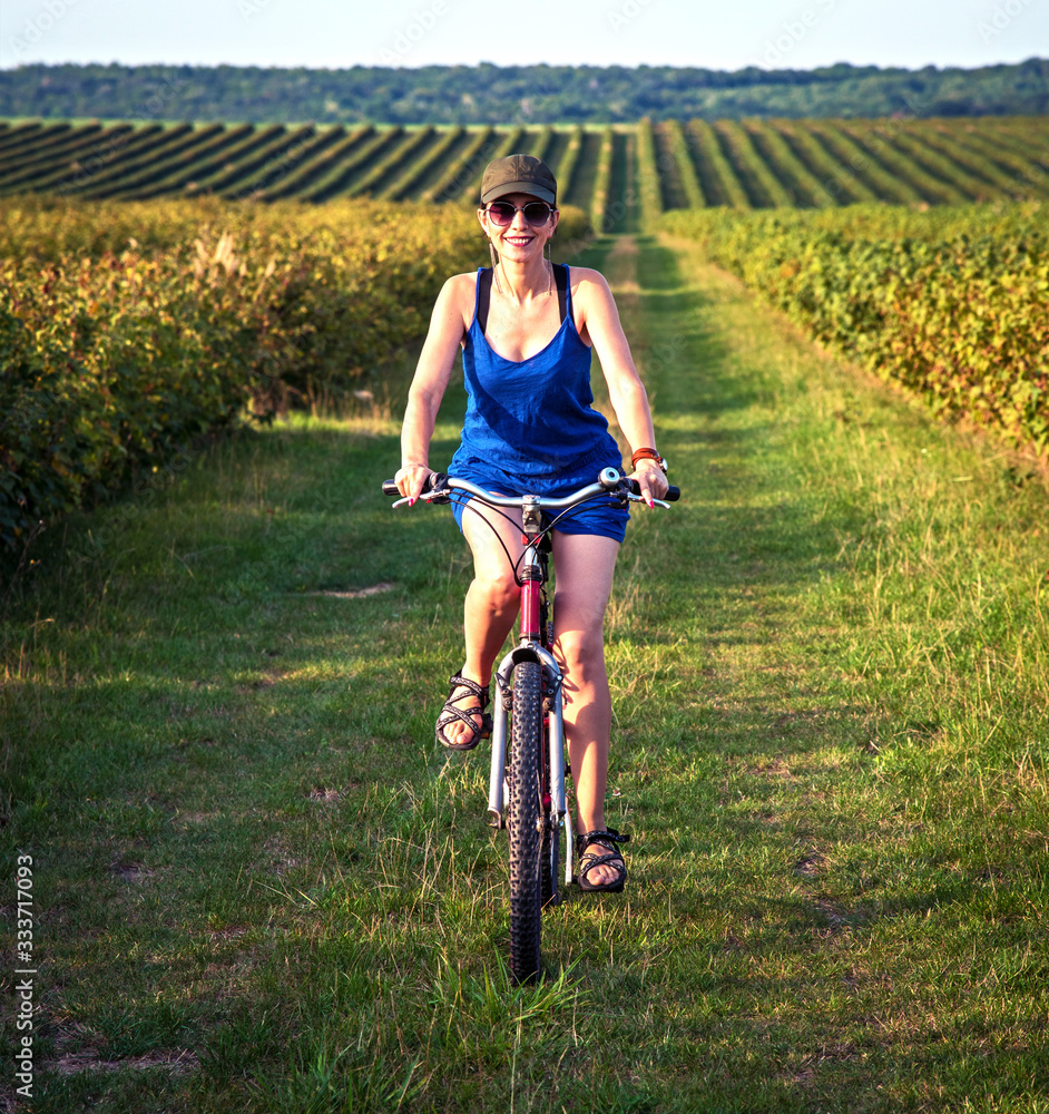 Carefree smiling girl cycling alone in a field among currant bushes in the garden. the best solution to escape from a coronavirus