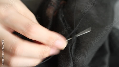  Woman sews up holes in black pants. Handmade sewing. Poverty and beggary concept.  photo