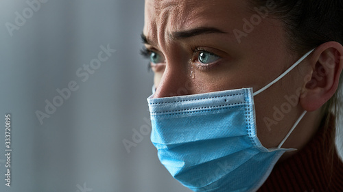 Canvas Print Upset depressed melancholy sad crying woman in protective face mask with tears eyes during illness, coronavirus outbreak and flu covid-19 epidemic