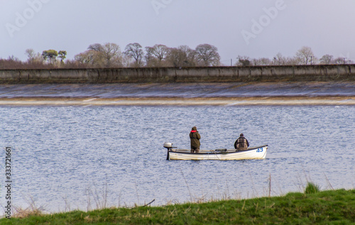 Two men fishing in a boat on a bright spring day