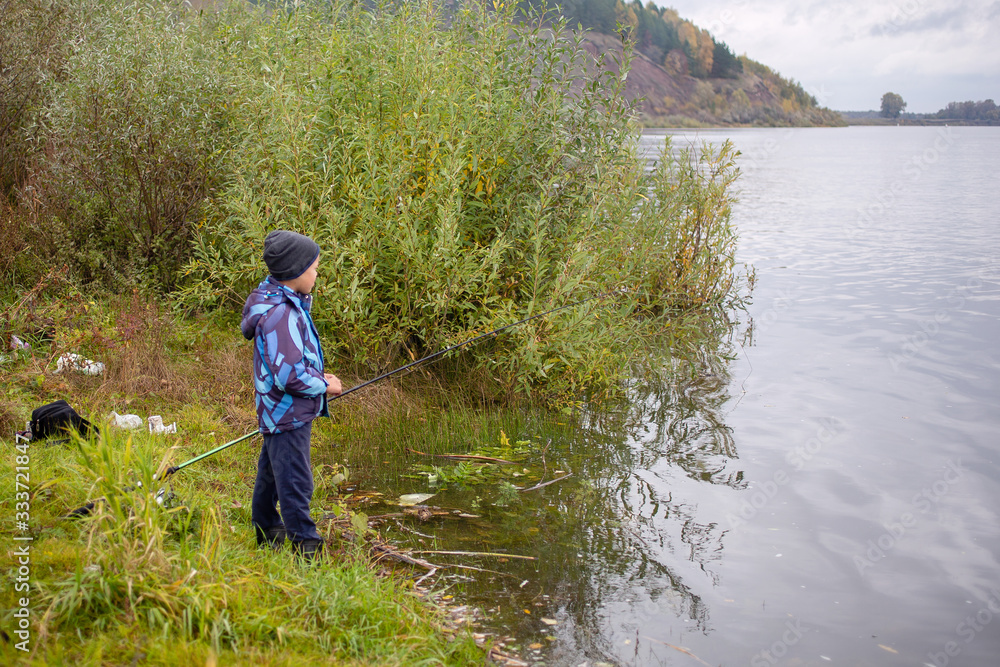 fishing kid on the river in autumn