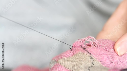  Woman sews up holes in pink socks. Handmade sewing. Poverty and beggary concept.  photo