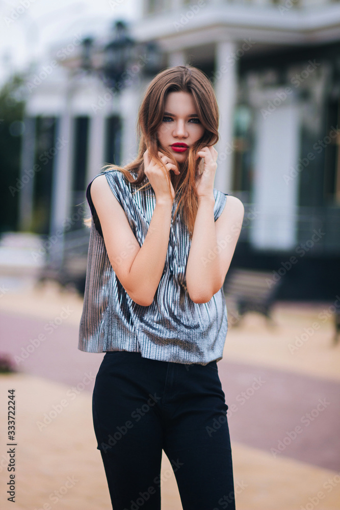 Fototapeta premium Beautiful, young, fashionable girl on the background of the building. Street fashion photo. Model with clean skin.