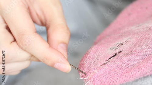  Woman sews up holes in pink socks. Handmade sewing. Poverty and beggary concept.  photo