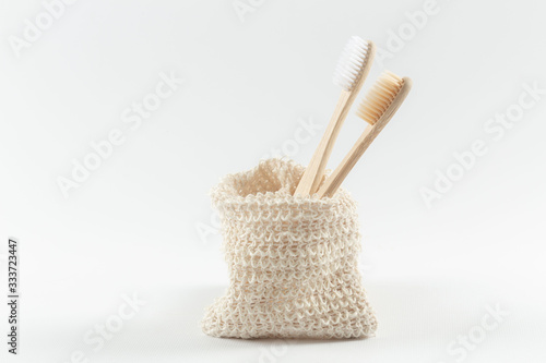 two natural wood toothbrushes lie in a row in an environmental bag. zero waste. on white background.