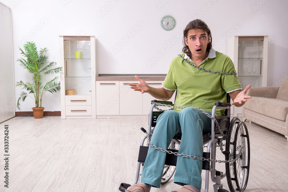 Young male invalid in wheel-chair suffering at home Young male invalid in wheel-chair suffering at home