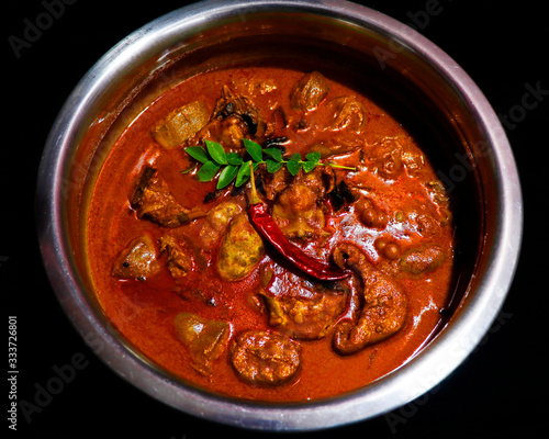 Kerala style spicy fish coconut curry in a metal pot with black background