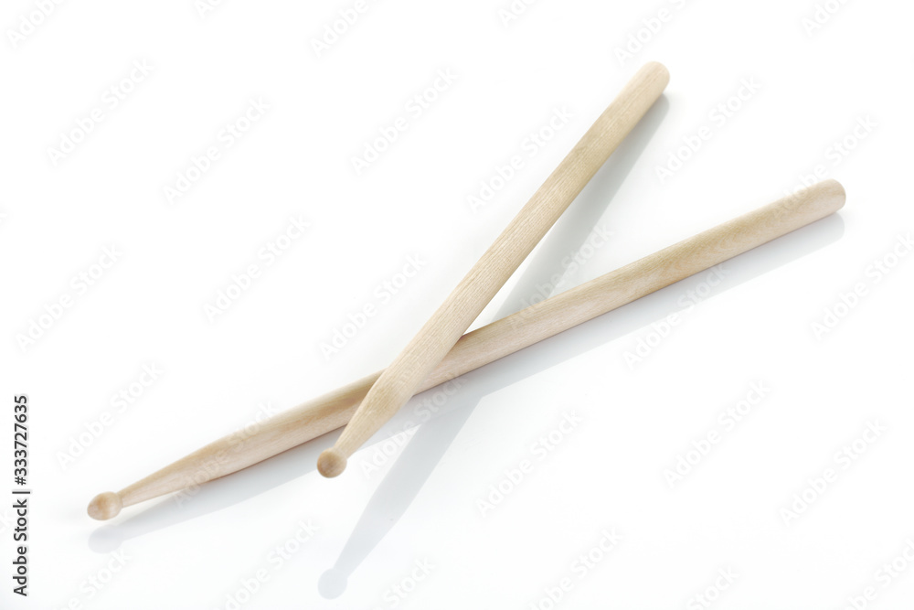pair of drumsticks on white surface with shadow
