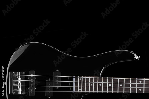 Black electric bass guitar on black background with copy space
