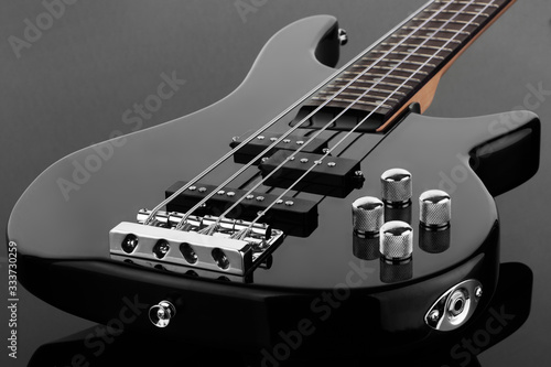 Body of black electric bass guitar on dark background