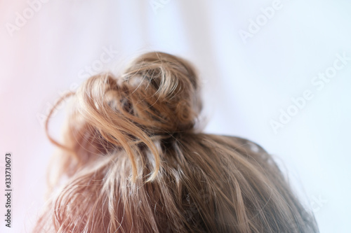 messy bun on the head of a blonde woman. quick hairdo at home because of quarantine. Modern fast hairstyle messy hair. bad hair day concept. 