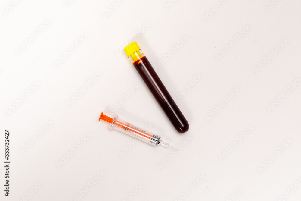 syringe for injection and test tube with blood, pills on a white background