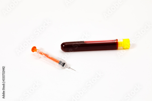 syringe for injection and test tube with blood, pills on a white background