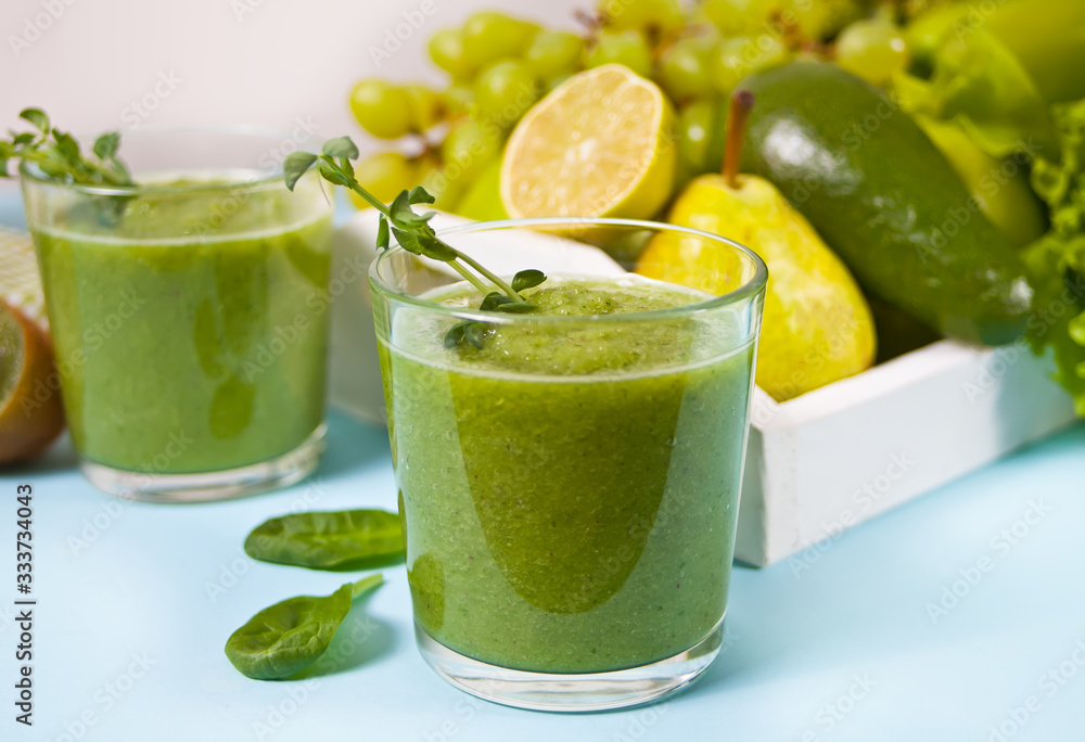 Fresh blended green smoothie in glasses with fruit and vegetables on the background. Health and detox concept. Fresh blended green smoothie in glasses with fruit and vegetables on the background. Health and detox concept.