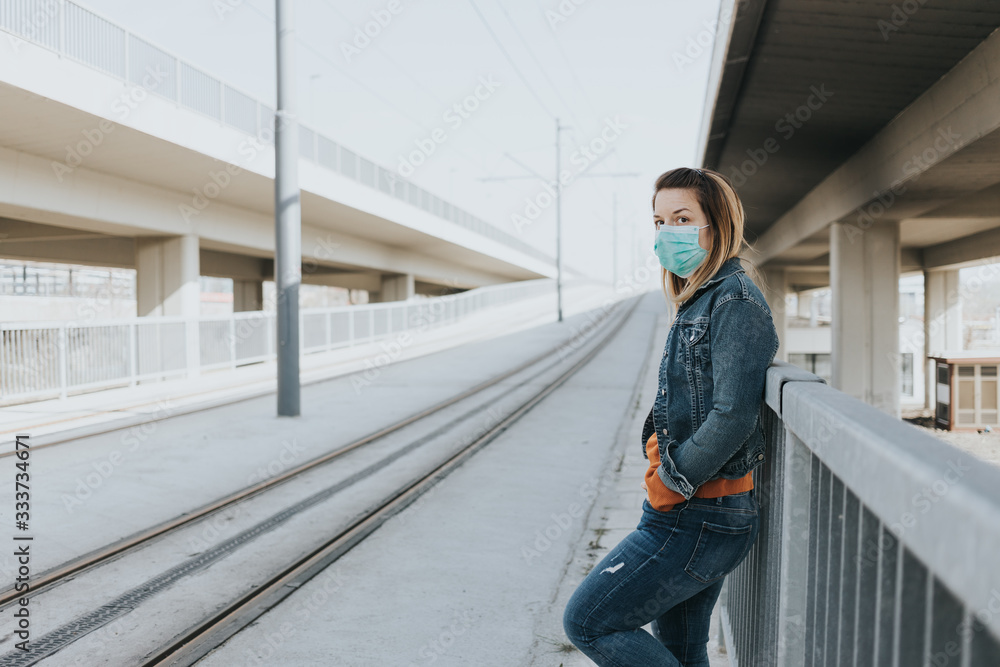 Obraz premium Young woman with a surgical mask in an empty tram station