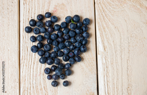 fresh ripe blueberries are scattered in the form of a heart on a wooden table