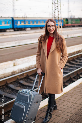 young girl standing at train station, portrait of tourist in coat