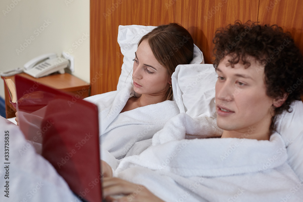 Family with laptop and book are lying at home. Weekend or isolation period. Remote learning and work. Selective focus on woman Family with laptop and book are lying at home. Weekend or isolation period. Remote learning and work. Selective focus on woman