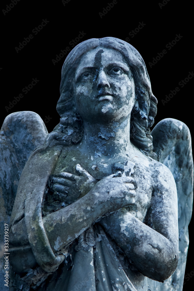 Ancient stone statue of praying angel isolated on black background.