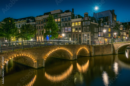 Night Amsterdam cityscape with bridges and houses on a canal.